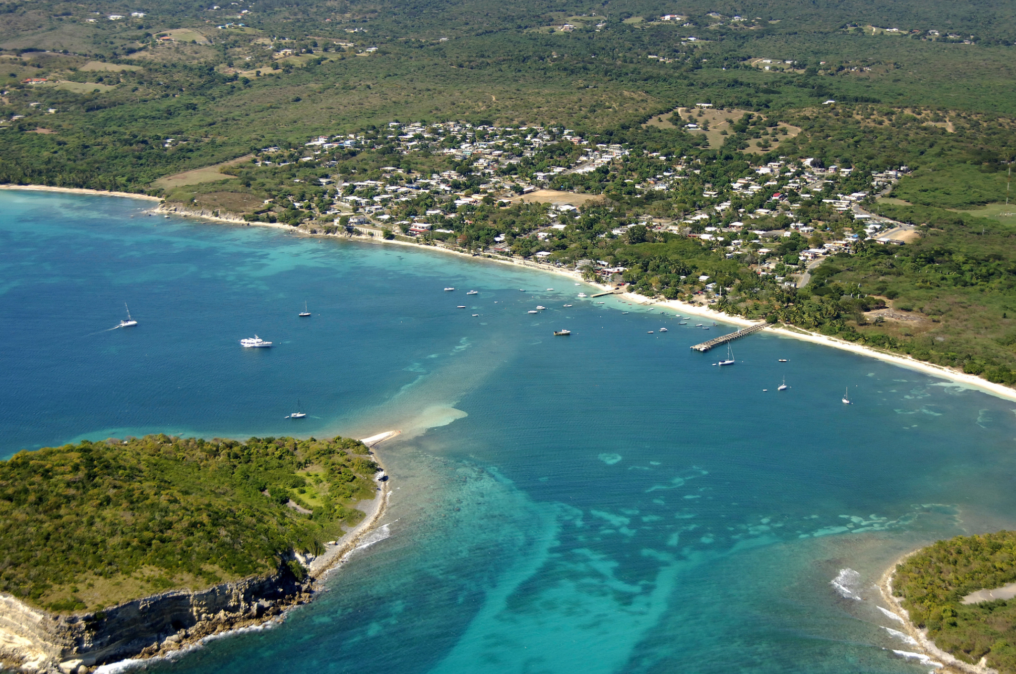 Aerial view of a coastal village, boats, piers, and turquoise water in Vieques